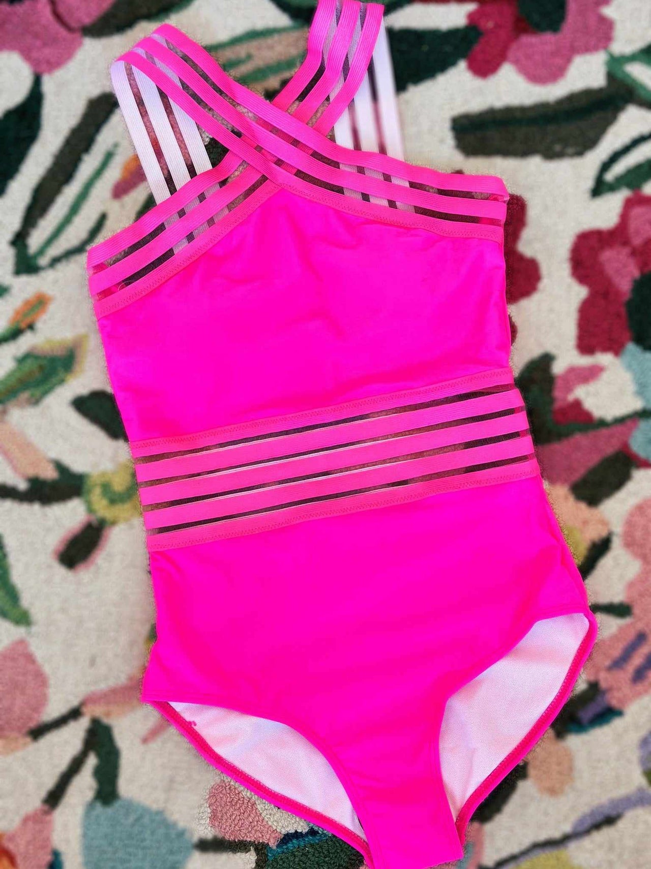 Pink one piece swimsuit with sheer striped waist and straps.