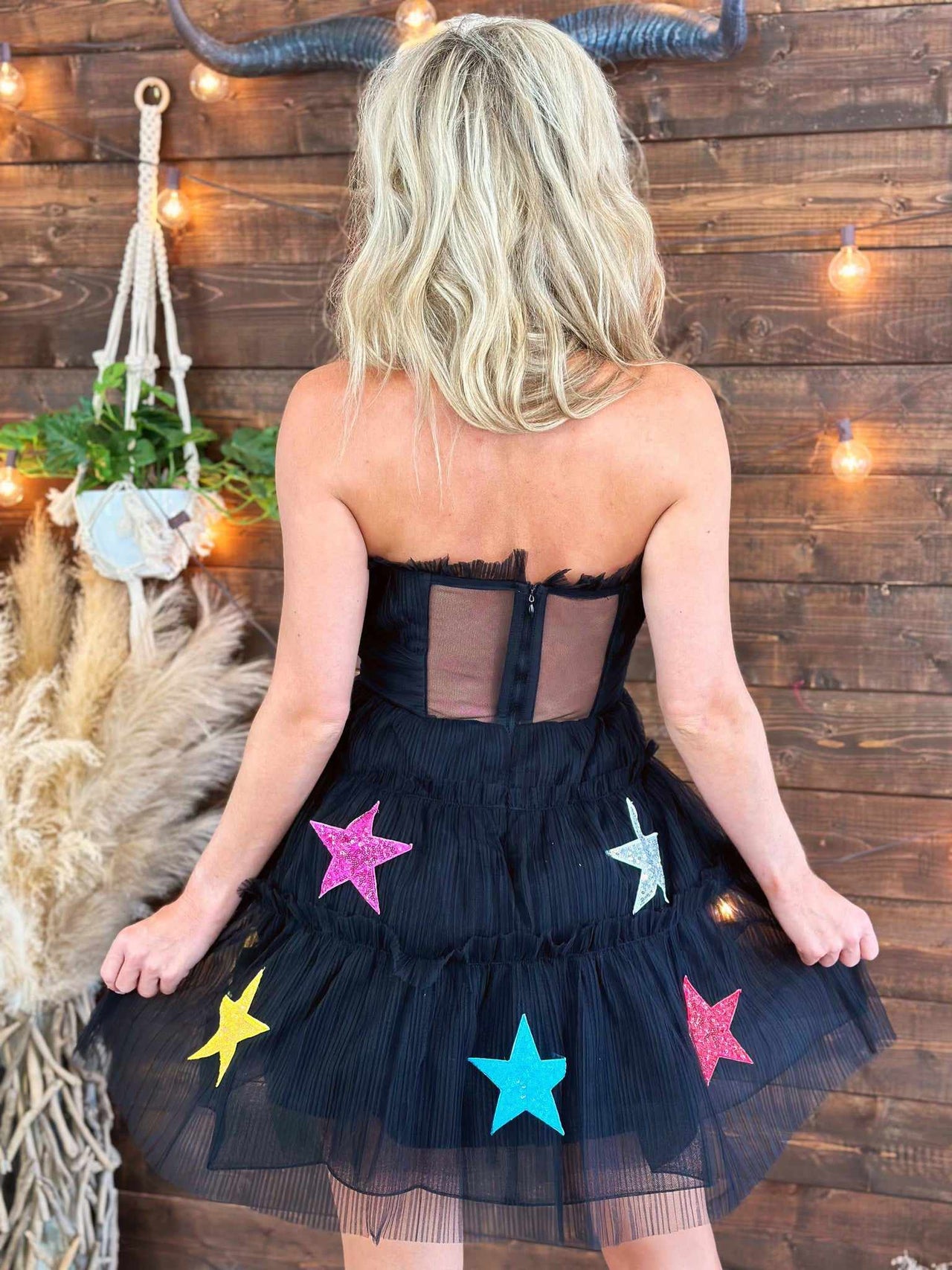 Strapless black mini dress with ruffles and stars.