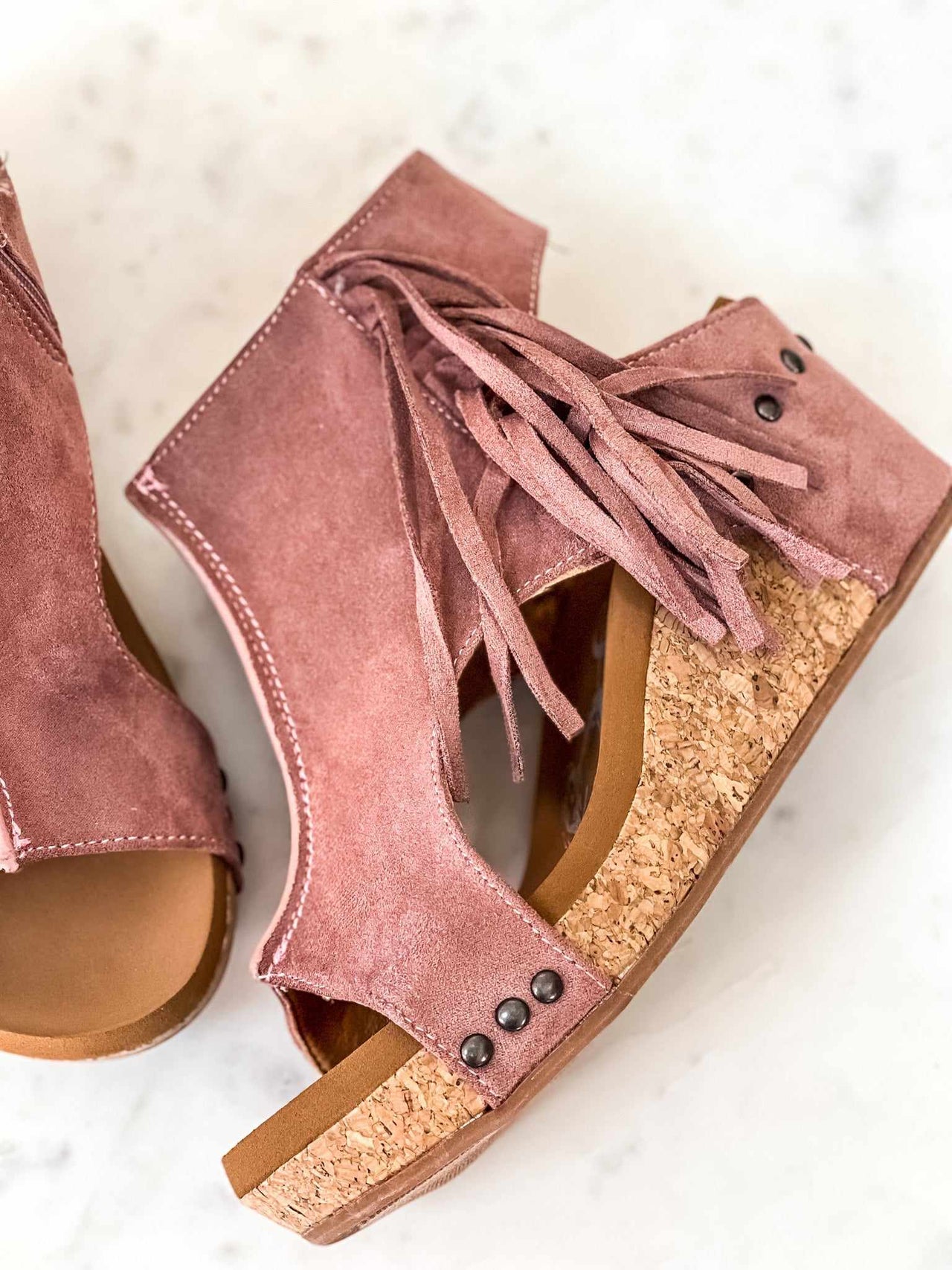 Blush pink suede wedge sandals with fringe.