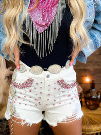 Thumbnail for Distressed white jean shorts with pink gem studs.
