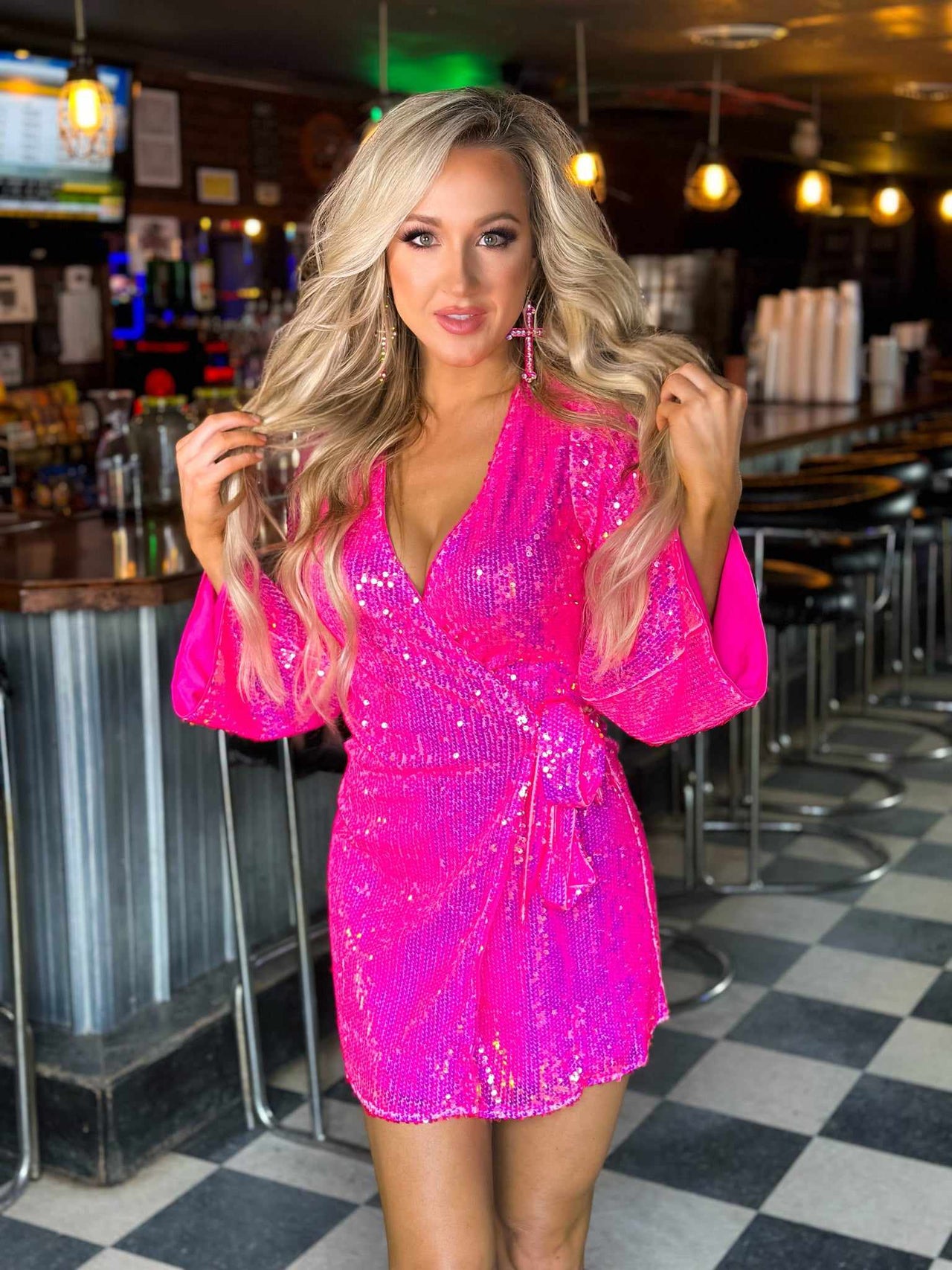 Pink sequin mini wrap dress with bell sleeves.