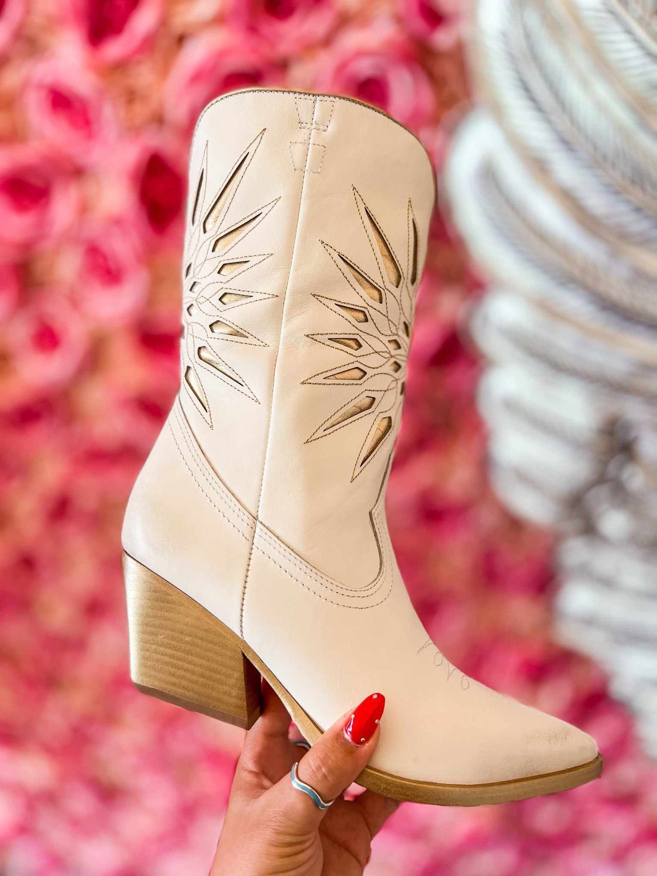Creamy white short western boots with starburst cutouts.