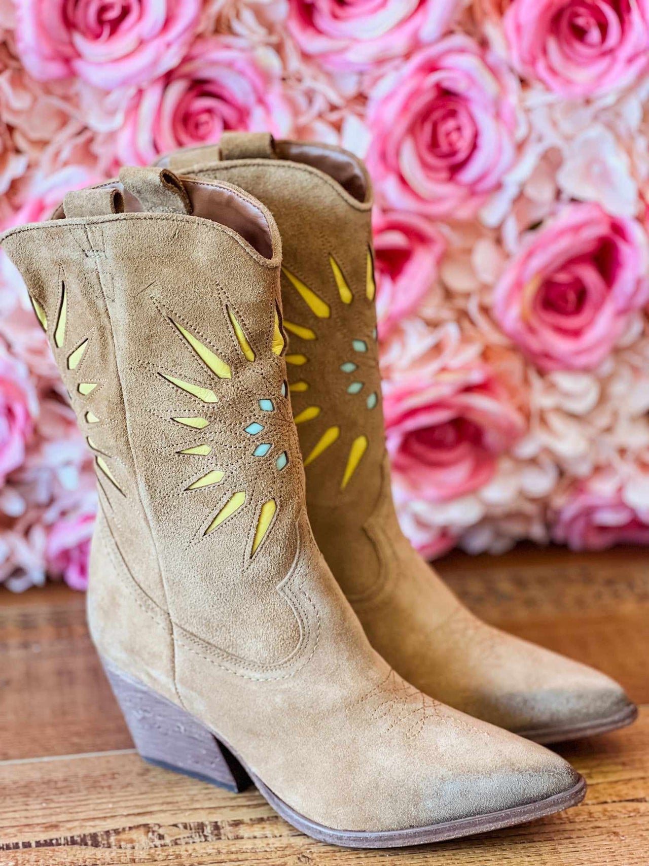 Brown suede short western boots with yellow and turquoise starburst pattern cutouts.