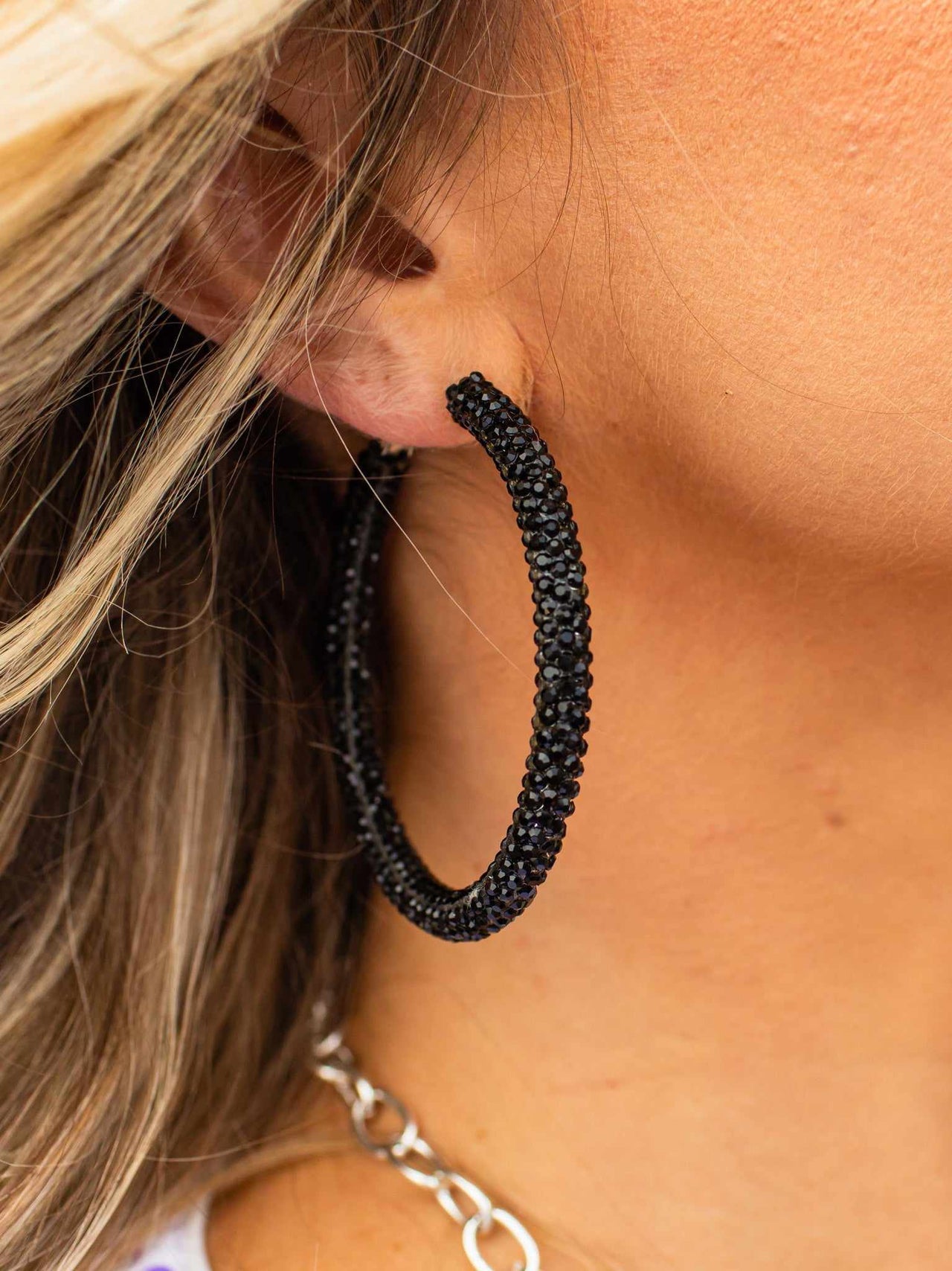 Crystal studded black hoop earrings.